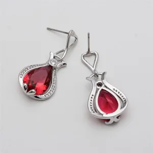 Detail shot of pear-shaped red zircon stud earrings with silver setting and sparkling crystal details.