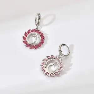 Close-up detail of silver peacock dangle earrings with vibrant red and pink cubic zirconia stones.