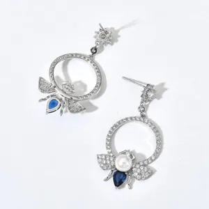 Detailed view of elegant silver-tone rhinestone bee earrings featuring pearls and blue crystal drops.