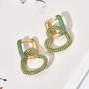 Detail shot of elegant gold-toned interlocking heart hoop earrings embedded with green zircon stones.