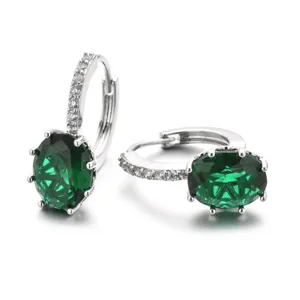 Detail view of elegant oval green zircon silver huggie earrings with pave stones.