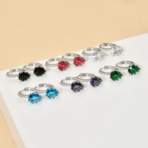 Primo piano dettagliato di orecchini a cerchio con zirconi a goccia in vari colori brillanti.