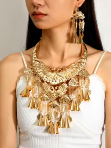 Detailed close-up shot of ethnic gold tone peacock necklace and long bell earrings set.