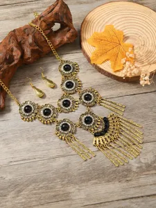 Detailed view of a bohemian vintage ethnic necklace and earrings set with gold alloy and black stones.