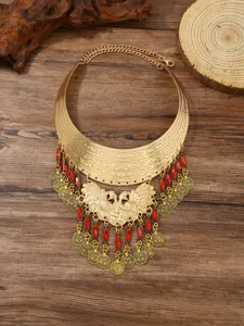 Close-up detail of vintage ethnic gold statement collar necklace with red stones and coins.