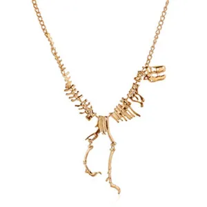 Detailed closeup of golden dinosaur skeleton pendant necklace, intricate vintage metal design.