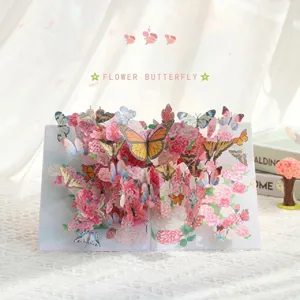 Carte de vœux pop-up 3D avec fleurs en papier faits main et papillons colorés.