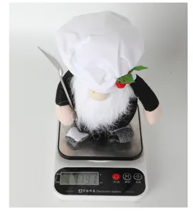 Primo piano del simpatico peluche gnomo cuoco con cappello bianco e forchetta, festa.