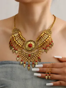 Vintage ethnic gold necklace and earrings set with red stones and intricate metal carving details.