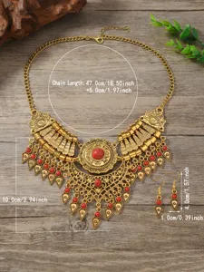 Vintage ethnic gold-tone necklace and earrings set with red stones and tassel pendants detail.