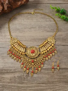 Vintage ethnic gold tone statement necklace and drop earrings set detailed shot on wood.