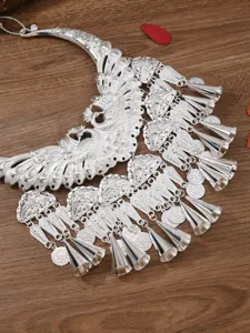 Detail shot of ethnic Miao silver peacock collar necklace with bells and coin pendants.