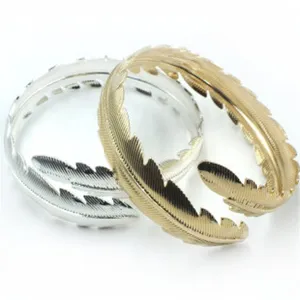 Detailed view of fashionable feather-shaped open cuff bracelets in gold and silver metal finish.