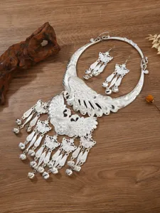 Detailed shot of ethnic Miao silver peacock necklace and tassel earrings set with bells.
