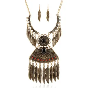 Close-up detail of vintage bohemian alloy feather pendant necklace and matching earrings set.