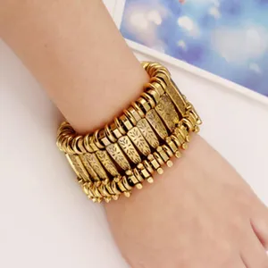 Close-up of a wide vintage gold-tone multi-strand cuff bracelet, intricate ethnic metal design.
