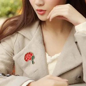 Detailed shot of elegant enamel carnation brooch pin, perfect Mother's Day accessory gift.
