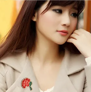 Elegant enamel carnation brooch detail shot, perfect worn on beige coat lapel for gifts.