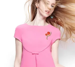 Detailed shot of a stylish carnation enamel crystal brooch worn on a pink dress for gifting.