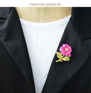 Exquisite rhinestone camellia brooch featuring vibrant pink petals and green leaves detail.