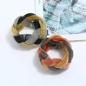 Chunky metallic woven statement cuff bracelet detail, multi-color interlocking metal wire design.