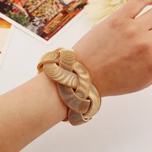 Gold metal woven cuff bracelet close up, fashion statement hand jewelry detail view.