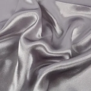 Nahaufnahme von glattem Satintuch Stoff, elegantes Drapieren und weiche schimmernde Oberflaeche.