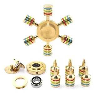 Brass mechanical fidget spinner detail view showing detachable piston parts and central bearing.