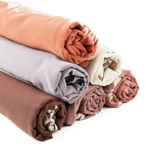Chiffon scarf detail showing rolled fabric stack in multiple colors with delicate embroidery edge.