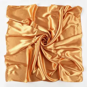 Vista dettagliata del lussuoso foulard in raso dorato, tessuto dalla texture liscia.