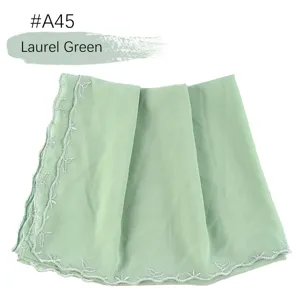Gedetailleerd overzicht van lauriergroene chiffon hijab met geborduurde kantrand.