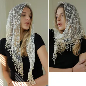 Gros plan détail du voile triangulaire en dentelle blanche avec broderie florale et franges.