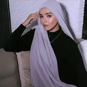 Detail shot of elegant chiffon hijab featuring sparkling rhinestone chain trim and soft texture.