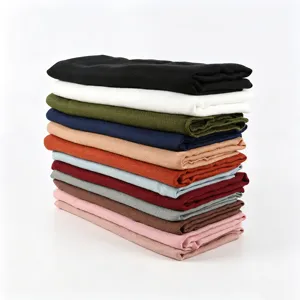 Vue détaillée d'une pile soignée de foulards carrés unis en coton et lin colorés.