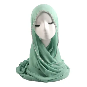 Close-up detail of mint green chiffon hijab trim with sparkling rhinestone chain edge elegance.