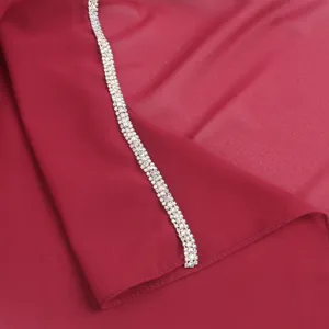 Close-up detail of elegant burgundy chiffon scarf with sparkling crystal rhinestone chain trim.