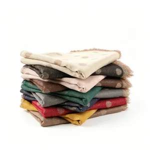 Close-up view of stacked metallic jacquard polka dot rayon scarves with fringe details.
