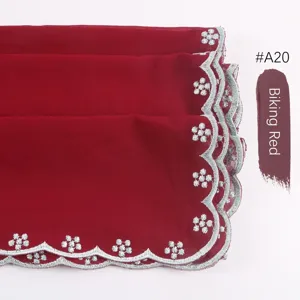 Detalle de pañuelo hijab de gasa con bordado plateado y borde festoneado color rojo.