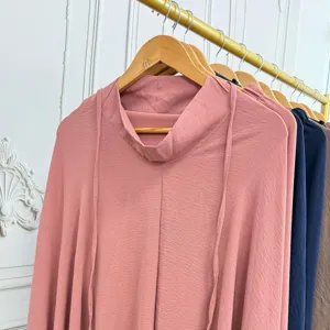 Close-up detail view of solid color long sleeve prayer dress with mock neck and strap.