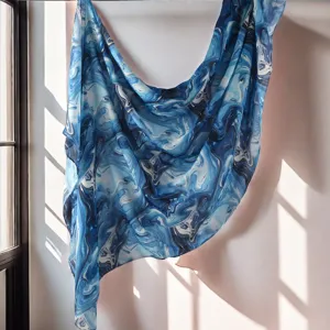 Blue marble print scarf detail shot, showing soft draping texture and elegant light shadows.