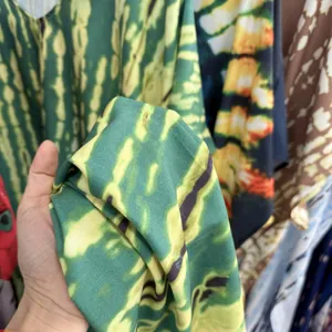 Close-up detail of green tie-dye beach cover-up fabric texture, showing vibrant vacation style.