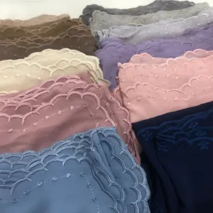 Primer plano detallado del hiyab de gasa bordado festoneado con perlas delicadas en colores.