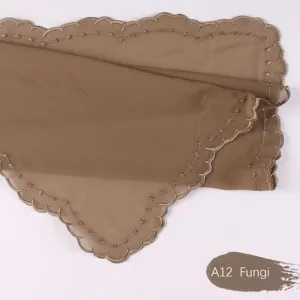 Primer plano detallado de la bufanda de gasa marrón con delicados bordes bordados.