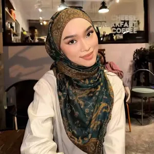 Detail view of a stylish green paisley jacquard scarf with elegant tassels for women.