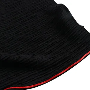 Close-up detail of black textured crinkle fabric shawl with red piped edge accent.