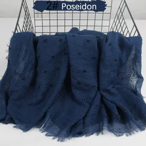 Lightweight blue crinkled cotton linen scarf with pom poms, breathable frayed shawl detail.