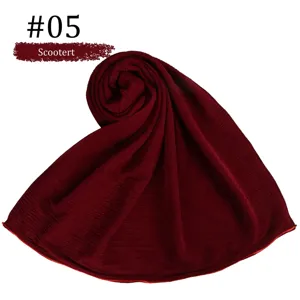 Detail shot of a dark red solid mercerized cotton rolled hijab shawl, soft and breathable fabric.