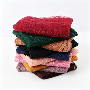 Detail view of colorful embroidered lace scarfs stacked neatly, showing thin breathable fabric.