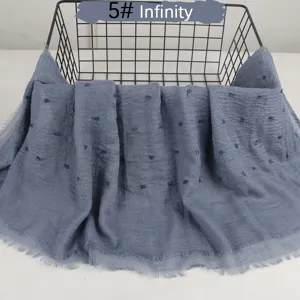 Solid color lightweight cotton linen scarf with crinkle pom poms and raw edge detail.