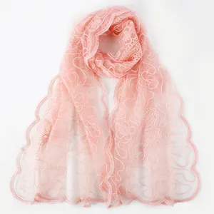 Pink floral embroidered lace scarf detail, delicate sheer mesh shawl texture closeup view.